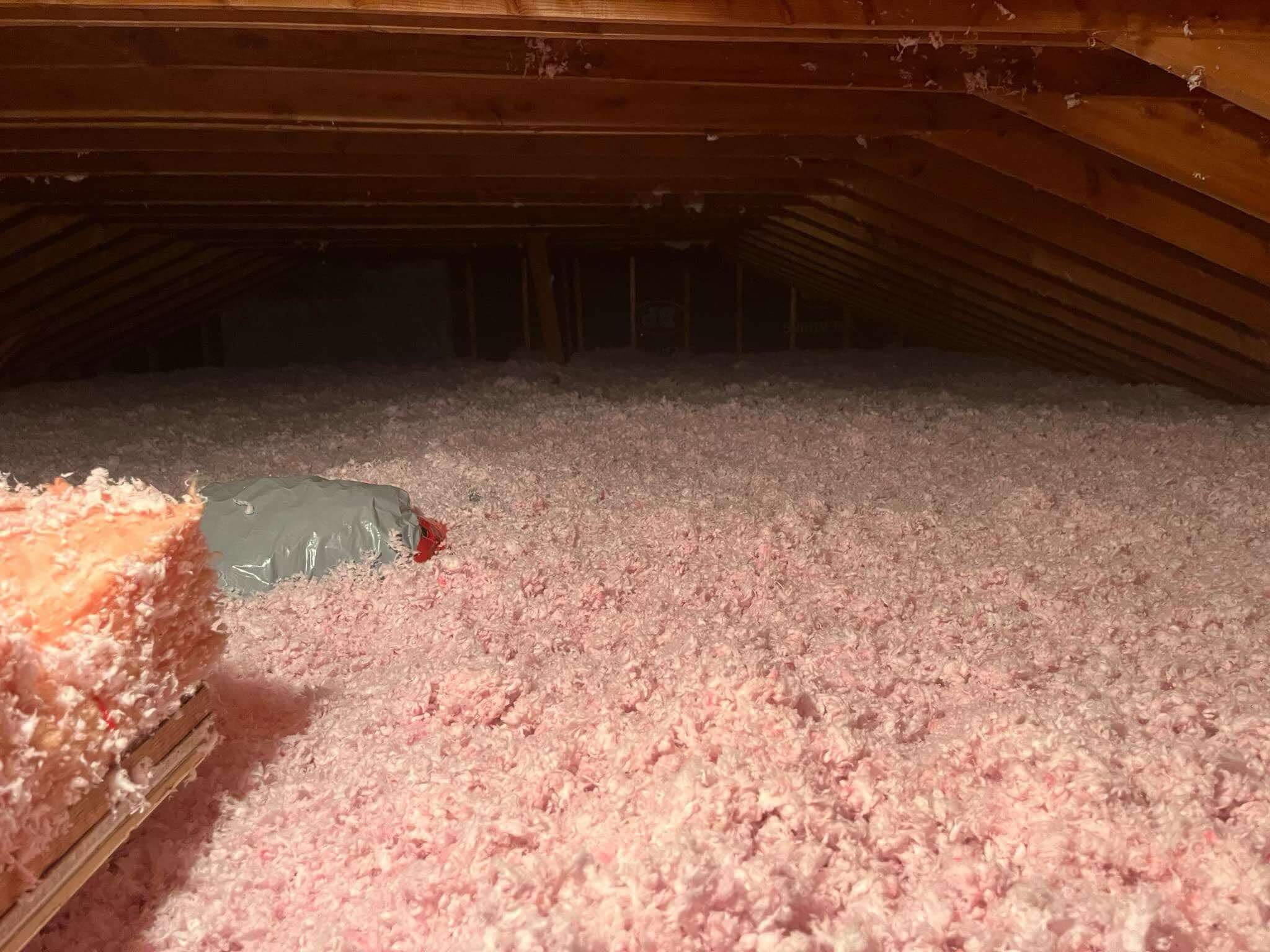 Attic floor fully covered in a thick, even layer of pink blown-in insulation