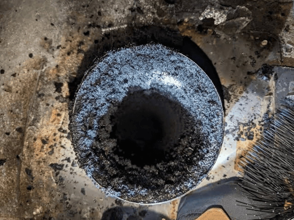 Chimney flue opening coated in creosote and soot before cleaning