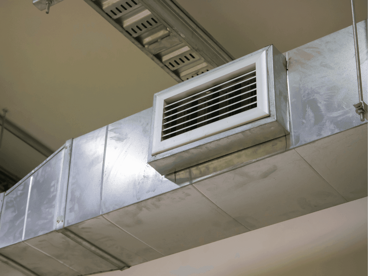 Exposed commercial ductwork with a supply air grille in a business ceiling