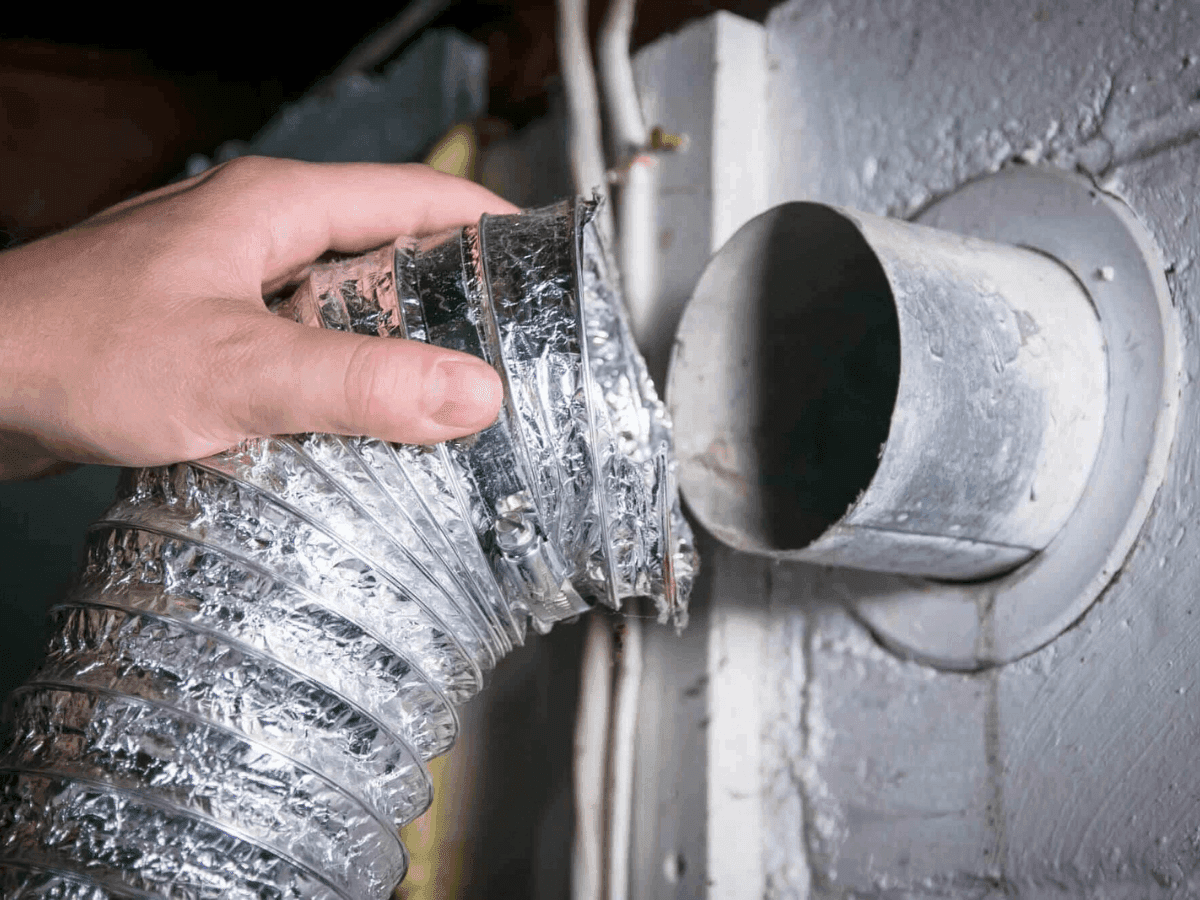Dryer vent hose being reconnected to the wall vent behind a dryer