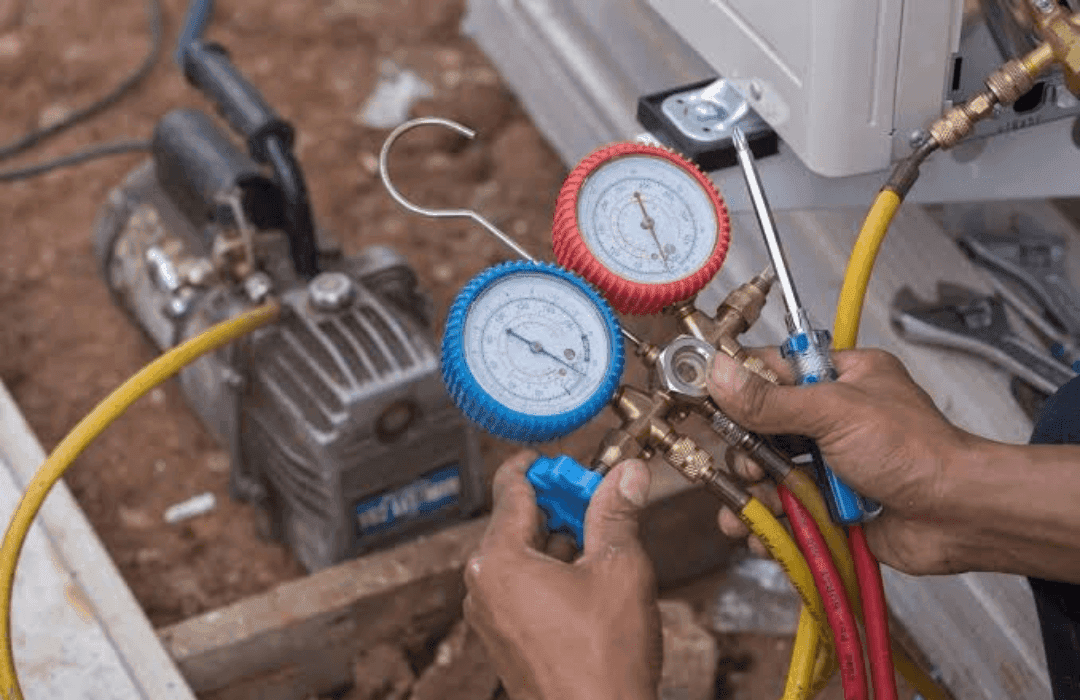 Technician checking system pressures with a gauge manifold during HVAC maintenance