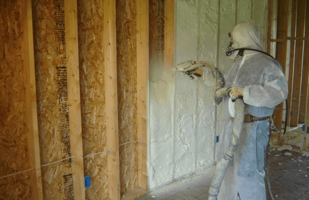Technician spraying closed-cell spray foam insulation between wall studs
