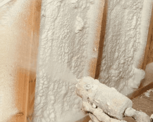 Closed-cell spray foam being applied between wall studs