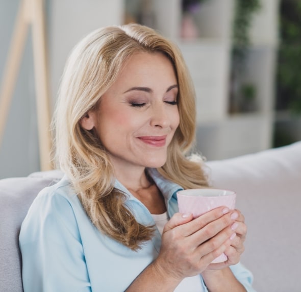 woman smiling with eyes closed and drink in hands